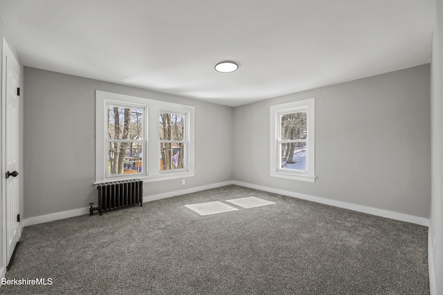 carpeted spare room featuring a healthy amount of sunlight, radiator, and baseboards