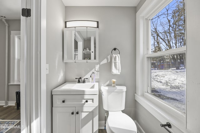 bathroom with toilet, vanity, baseboards, and wood finished floors