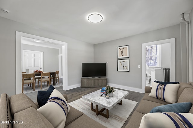 living area featuring baseboards, dark wood-style floors, and stairs