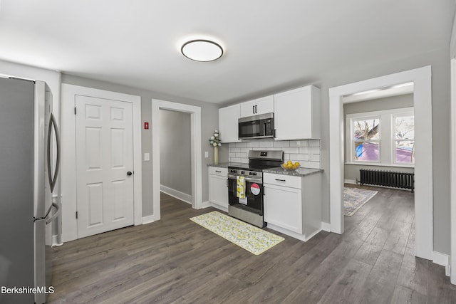 kitchen with backsplash, stainless steel appliances, radiator, white cabinets, and dark wood-style flooring