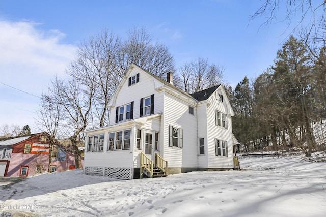 view of front facade featuring entry steps, a chimney, and a sunroom