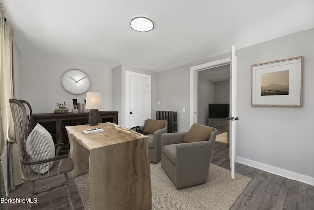 home office featuring radiator heating unit, baseboards, and wood finished floors