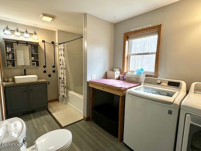 clothes washing area featuring a sink, separate washer and dryer, laundry area, and light wood-style flooring