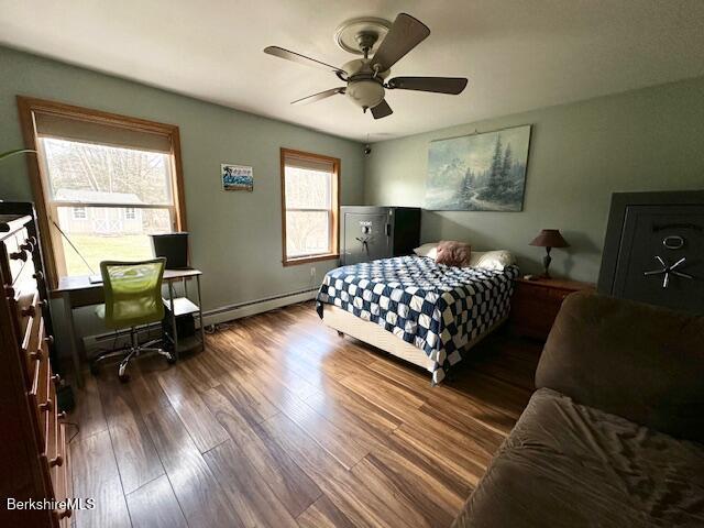 bedroom featuring baseboard heating, a ceiling fan, and wood finished floors