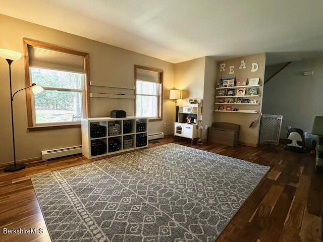 living area featuring wood finished floors, baseboards, a baseboard heating unit, and baseboard heating