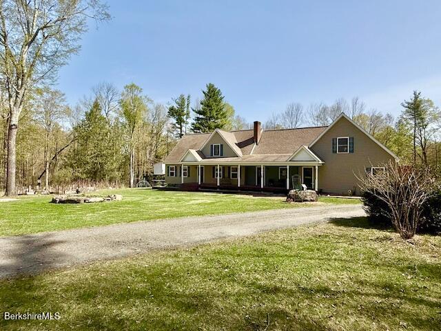 cape cod house with covered porch, a chimney, a front yard, and dirt driveway