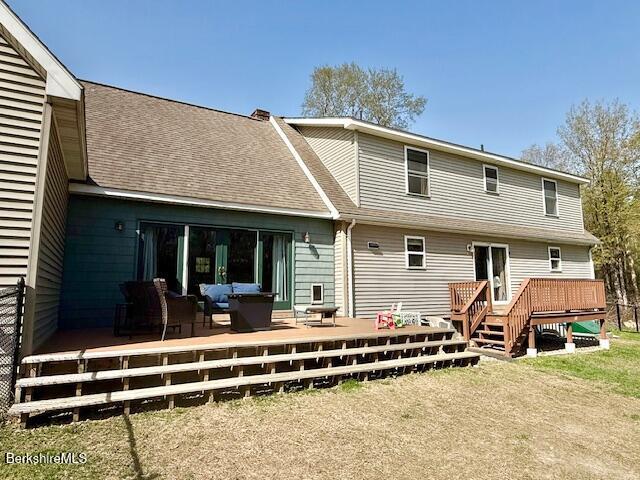 back of property with a deck, a shingled roof, and an outdoor hangout area