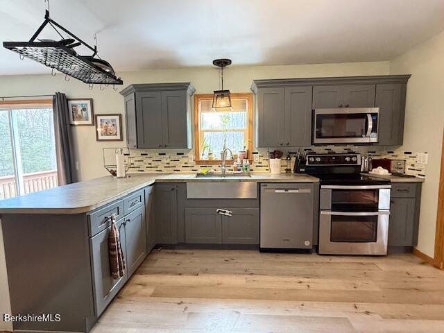 kitchen featuring a sink, appliances with stainless steel finishes, a peninsula, and a healthy amount of sunlight