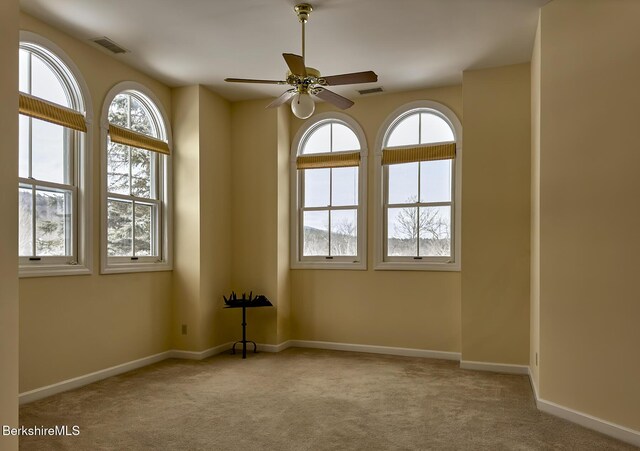 interior space with plenty of natural light, light colored carpet, lofted ceiling, and ceiling fan