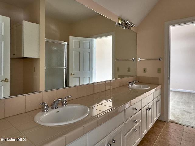 bathroom with tile patterned flooring, vaulted ceiling, vanity, and walk in shower