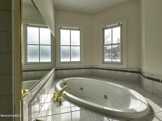 bathroom with a relaxing tiled tub and a healthy amount of sunlight