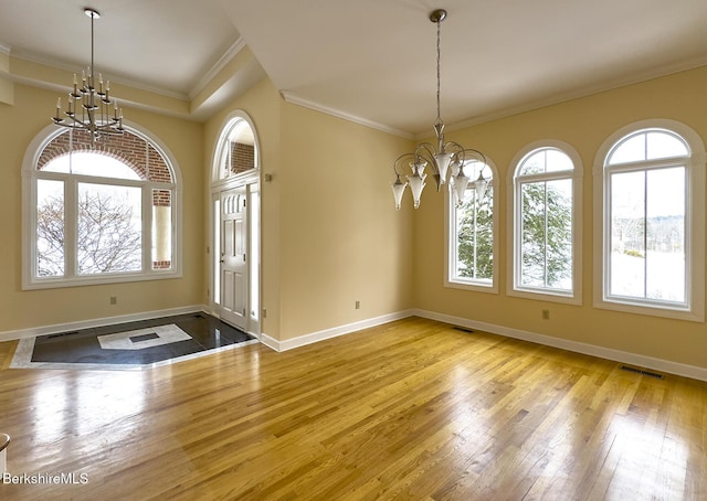 unfurnished dining area featuring an inviting chandelier, crown molding, and light wood-type flooring