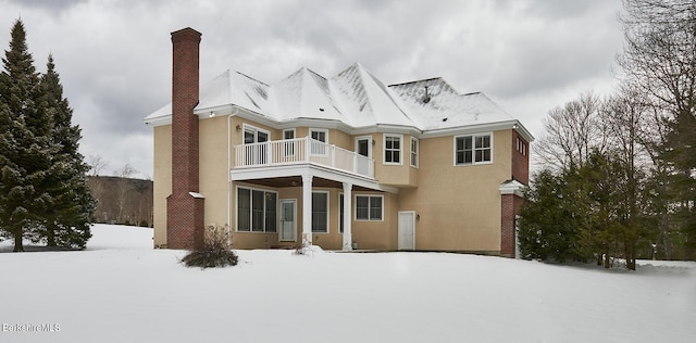 snow covered back of property with a balcony