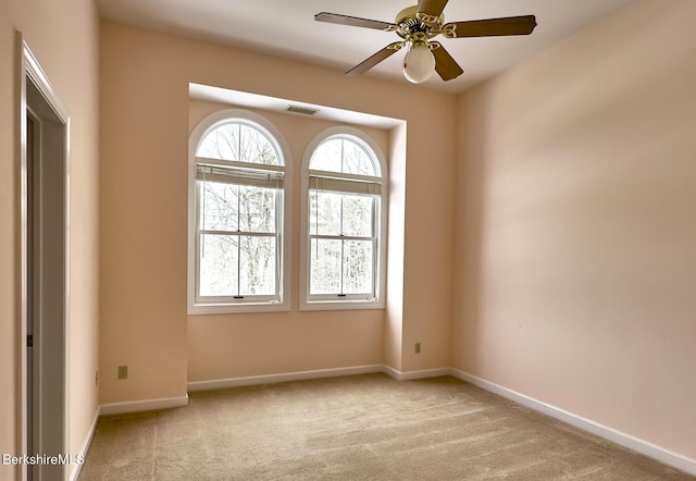 empty room with ceiling fan and light carpet