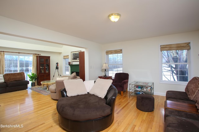 living room featuring light wood-type flooring, a fireplace, and baseboards