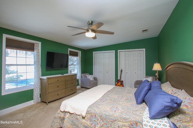 bedroom featuring lofted ceiling, multiple windows, two closets, and light carpet