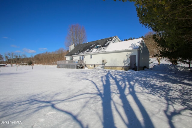 snow covered rear of property with a deck