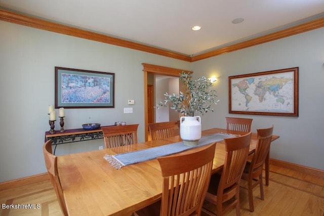 dining space featuring light wood-type flooring and crown molding