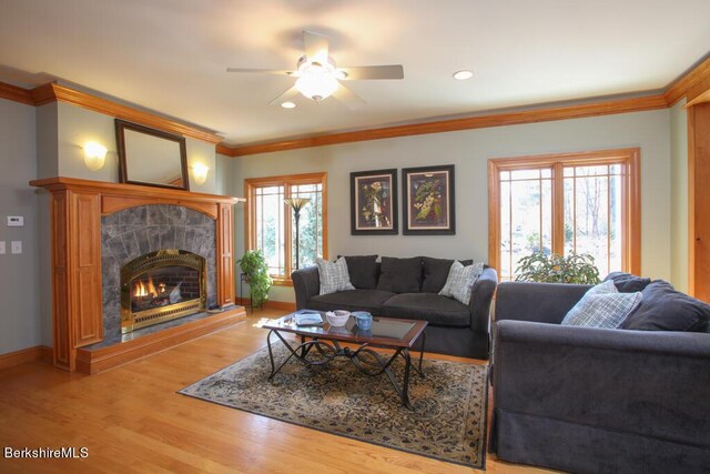 living room featuring wood-type flooring, plenty of natural light, ornamental molding, and ceiling fan