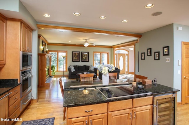 kitchen with dark stone counters, ceiling fan, light hardwood / wood-style floors, stainless steel appliances, and beverage cooler