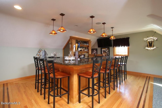 bar with light hardwood / wood-style flooring, hanging light fixtures, and lofted ceiling