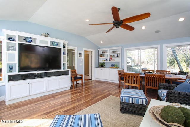 living room featuring ceiling fan, light hardwood / wood-style floors, and lofted ceiling