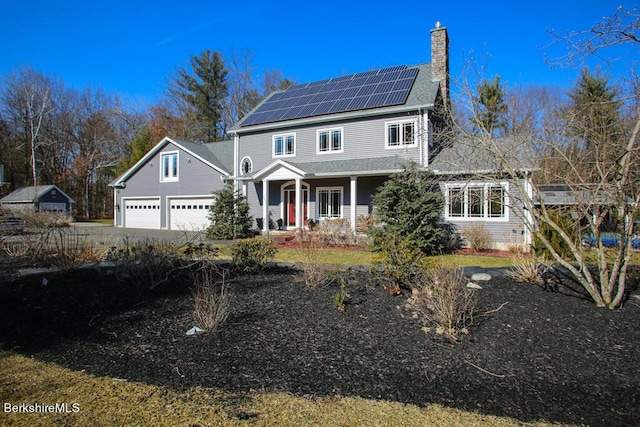 view of front of home featuring a garage, a porch, and solar panels