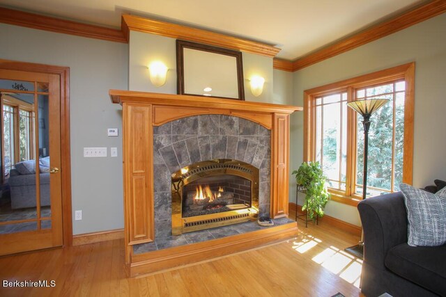 interior space featuring a tile fireplace, crown molding, and hardwood / wood-style flooring