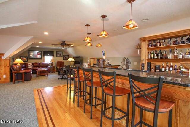 bar featuring ceiling fan, pendant lighting, vaulted ceiling, and light carpet