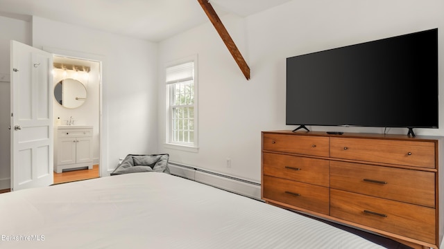 bedroom with ensuite bath, baseboard heating, and sink