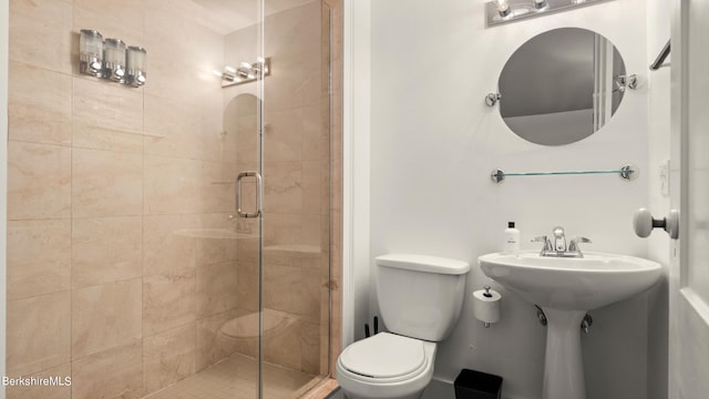 bathroom with sink, a shower with shower door, and toilet