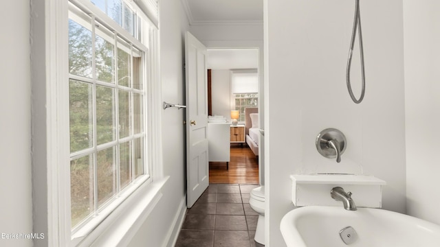 bathroom featuring tile patterned floors, toilet, crown molding, and a wealth of natural light