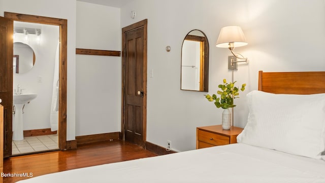 bedroom with ensuite bathroom and wood-type flooring