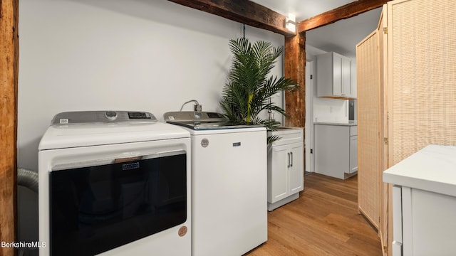 washroom with light hardwood / wood-style flooring, cabinets, and independent washer and dryer