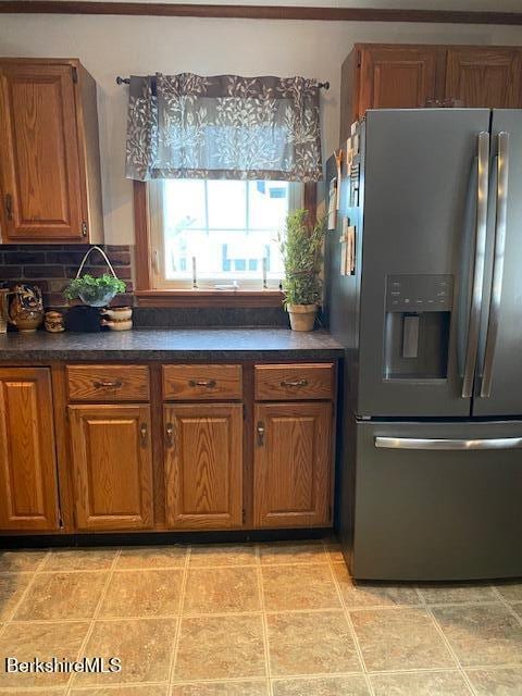 16 Woodlawn Ave, North Adams, MA 01247 - kitchen with stainless steel fridge, dark countertops, brown cabinets, light tile patterned flooring, and tasteful backsplash