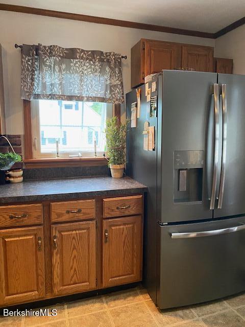 16 Woodlawn Ave, North Adams, MA 01247 - kitchen with stainless steel refrigerator with ice dispenser, brown cabinetry, dark countertops, crown molding, and light tile patterned flooring