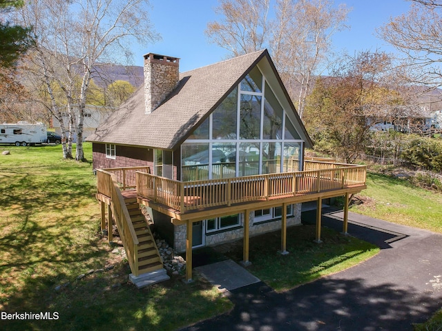 rear view of house featuring a chimney, a lawn, stairs, and a deck