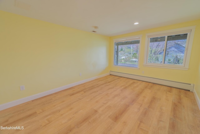 empty room with recessed lighting, baseboards, light wood-type flooring, and a baseboard radiator