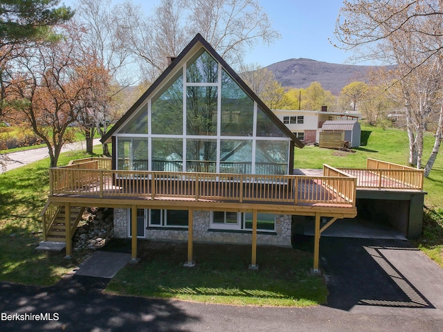 back of property with stairs, a deck with mountain view, an outbuilding, and stone siding