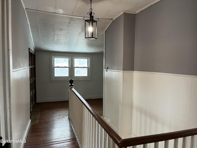 hallway featuring baseboards, dark wood finished floors, and an upstairs landing