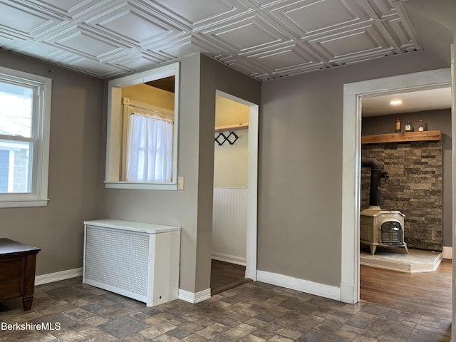 interior space with a wood stove, plenty of natural light, an ornate ceiling, and baseboards