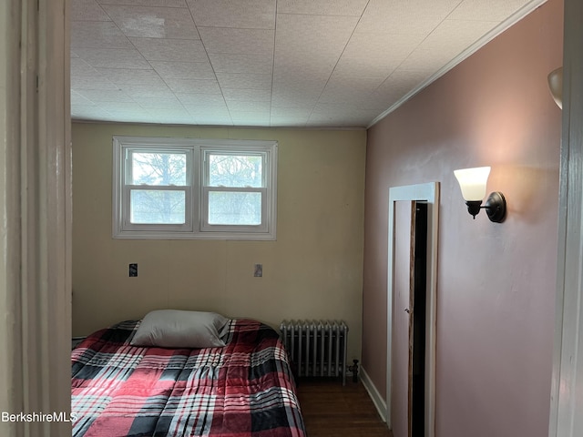 bedroom featuring radiator heating unit and wood finished floors