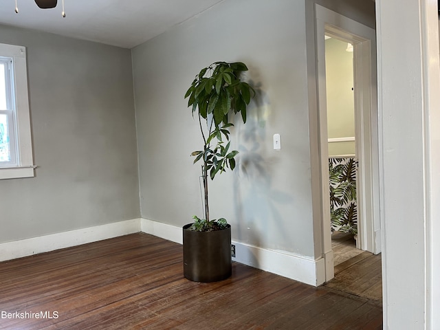 unfurnished room with a ceiling fan, baseboards, and dark wood-type flooring