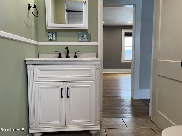 bathroom with baseboards, wood finished floors, and vanity