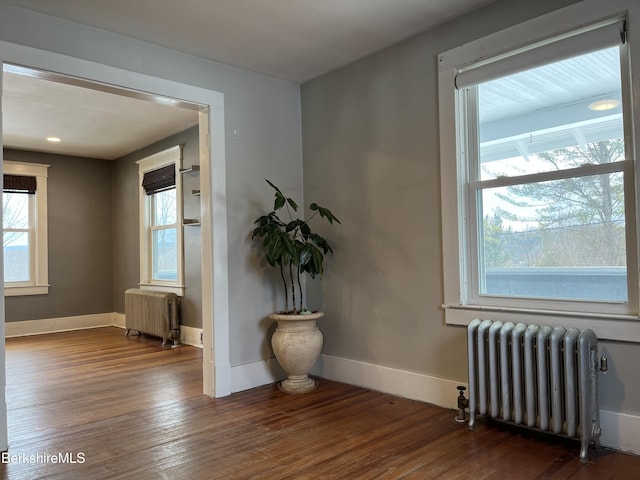 spare room with baseboards, hardwood / wood-style floors, and radiator heating unit