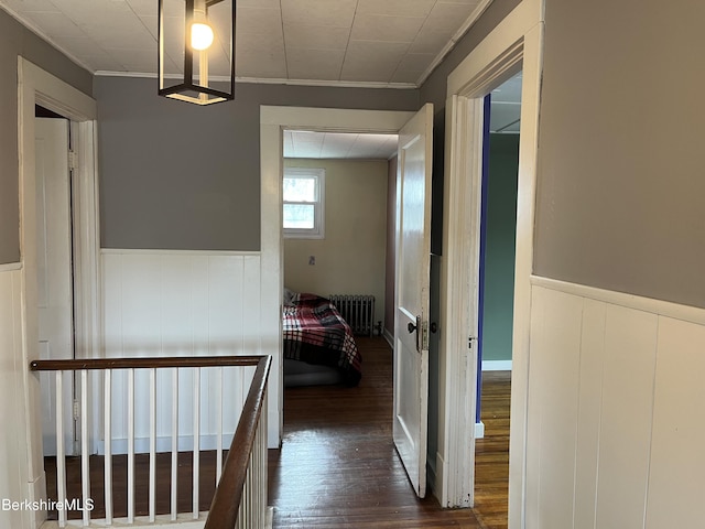 corridor featuring ornamental molding, radiator, wainscoting, and wood finished floors