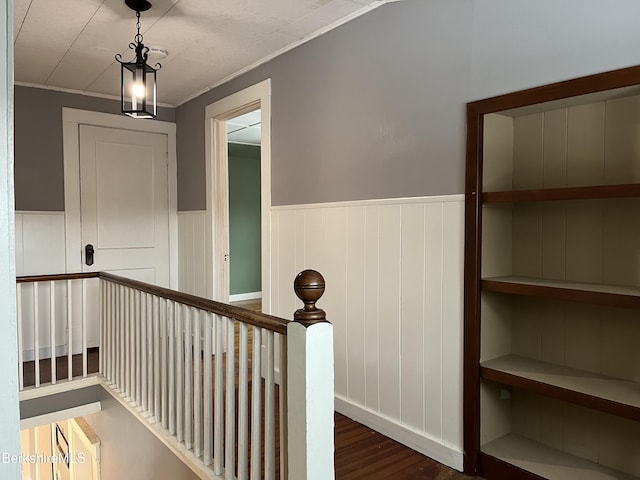 hallway featuring a wainscoted wall, crown molding, an upstairs landing, and wood finished floors