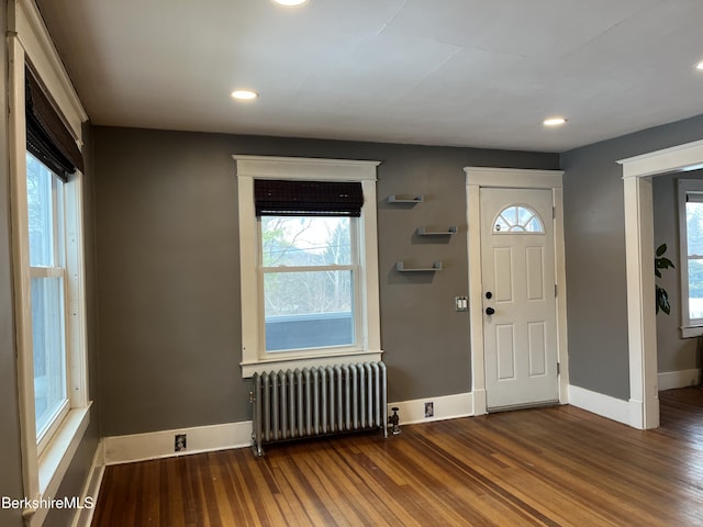 foyer featuring radiator heating unit, baseboards, wood finished floors, and recessed lighting