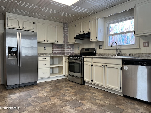 kitchen featuring under cabinet range hood, stainless steel appliances, a sink, stone finish floor, and an ornate ceiling