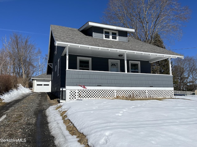 view of front of property with covered porch, a shingled roof, an outdoor structure, and a garage